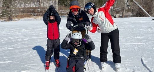 Four skiers in ski gear on a snowy slope.