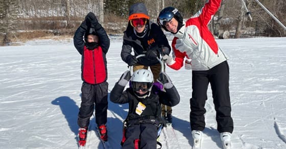 Dr. Christopher Najarian with children in adaptive ski gear on a snowy slope.