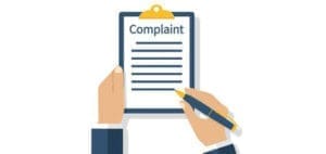 Hands filing a complaint on a clipboard.