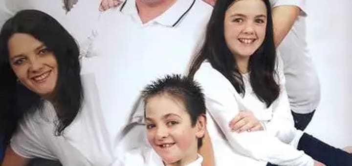 Zachary and his family in white shirts smiling.