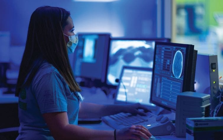 Dr. Susan Apkon in a medical setting reviewing scans on a computer.