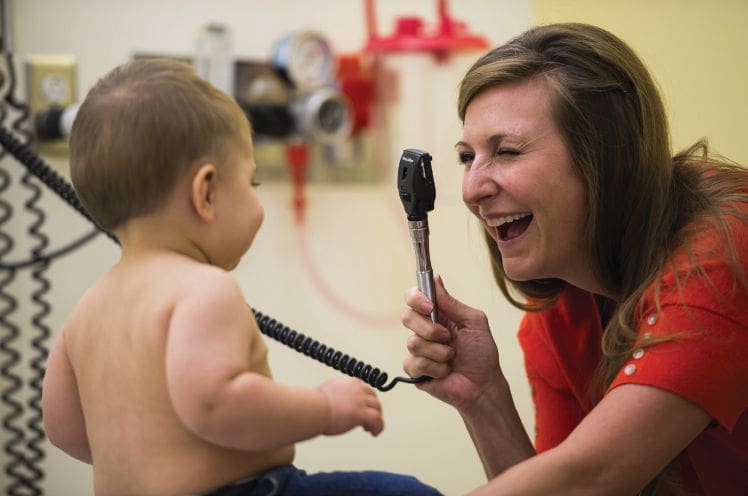 Dr. Susan Apkon interacts with a baby in a medical exam room.
