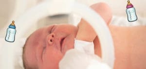 Newborn baby in incubator with feeding bottles