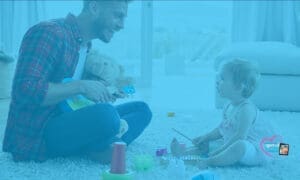 A father and his young child play with toys on the floor.