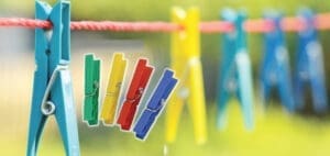 Clothesline with colorful clothespins and a blue clothespin in the foreground.
