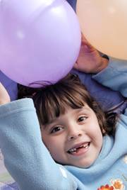Child playing with purple and peach-colored balloons.