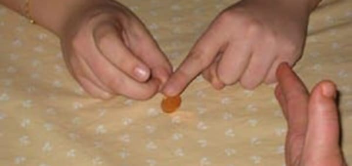 Fingers flicking a penny on a patterned surface.
