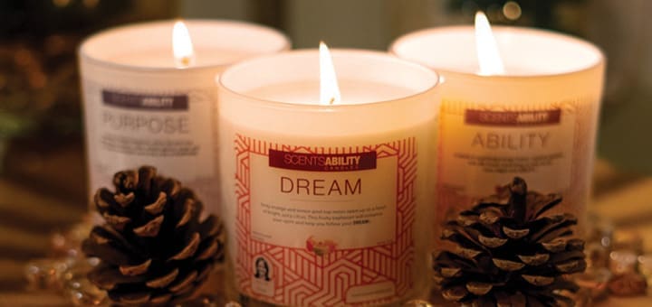 Three lit candles, labeled "Purpose," "Dream," and "Ability," sit in a decorative arrangement with pinecones.