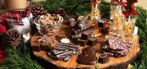 Chocolate charcuterie board with assorted chocolates, nuts, and festive decorations.