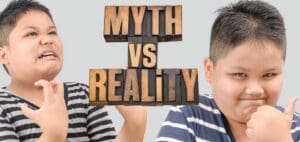 Two children with wooden block letters spelling "MYTH VS REALITY" between them.