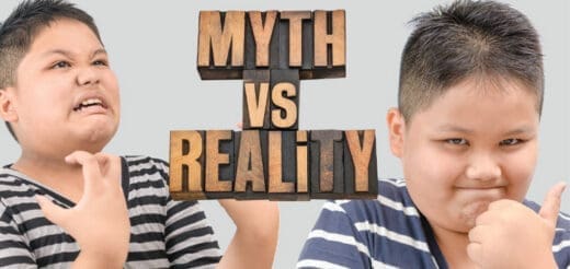 Two children with wooden block letters spelling "MYTH VS REALITY" between them.