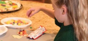 A child decorates cookies with candy.