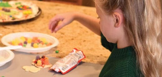 A child decorates cookies with candy.