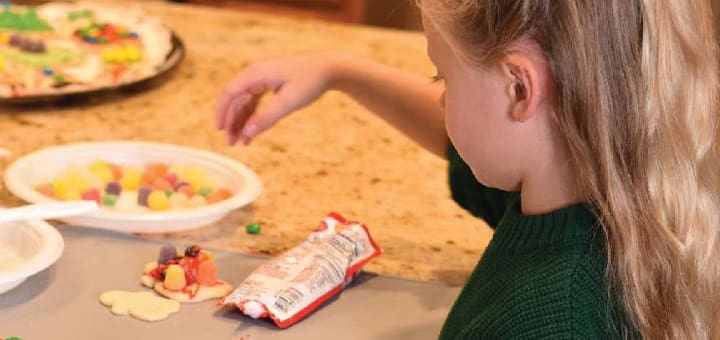 A child decorates cookies with candy.