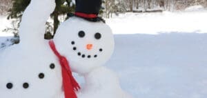 Snowman wearing a black top hat and red scarf outdoors in the snow