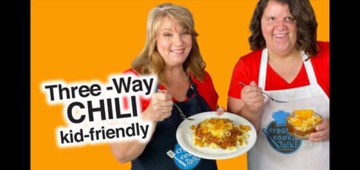 Two women smiling with plates of chili.