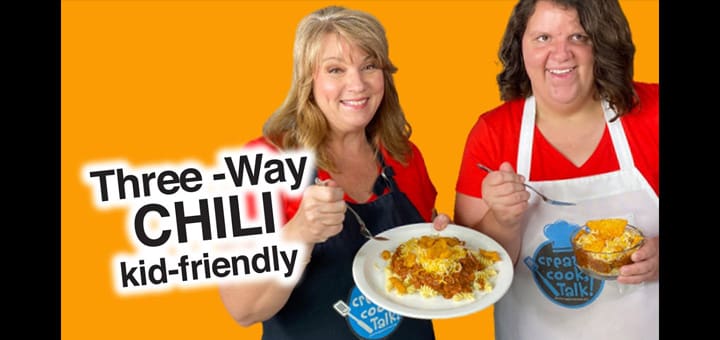 Two women smiling with plates of chili.