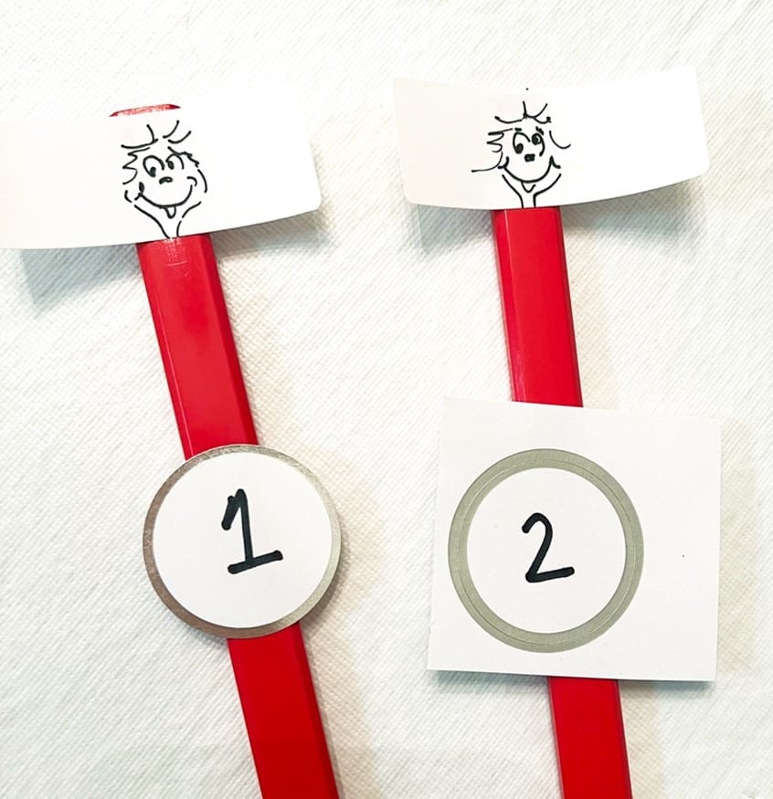 Two red pencils topped with Thing 1 and Thing 2 faces and numbers.