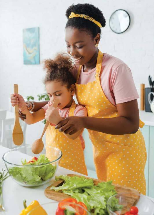 Mother and daughter in yellow polka-dot aprons prepare a salad in the kitchen.