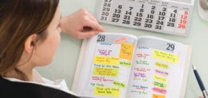 Woman marking calendar entries in a planner.
