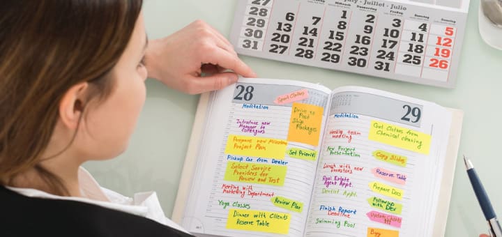 Woman marking calendar entries in a planner.