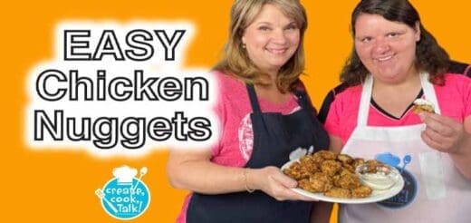 Two women hold a plate of chicken nuggets and a dip.
