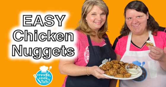 Two women smile holding a plate of chicken nuggets