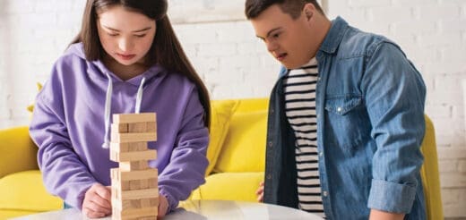 Two people playing Jenga on a table.
