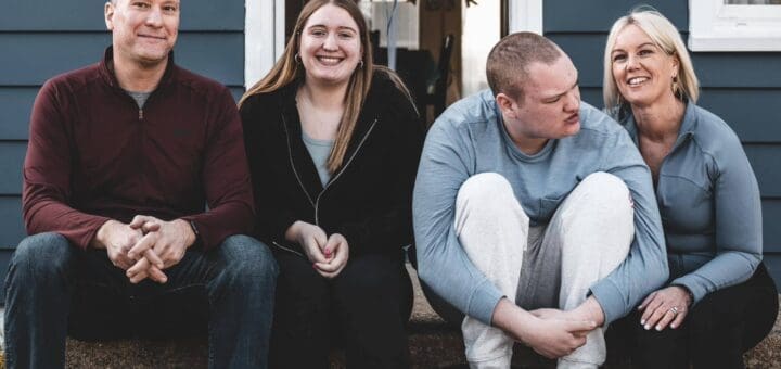 Amy Shope and three others sit on steps outside a blue house.
