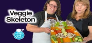 Two women present a Halloween veggie skeleton appetizer.