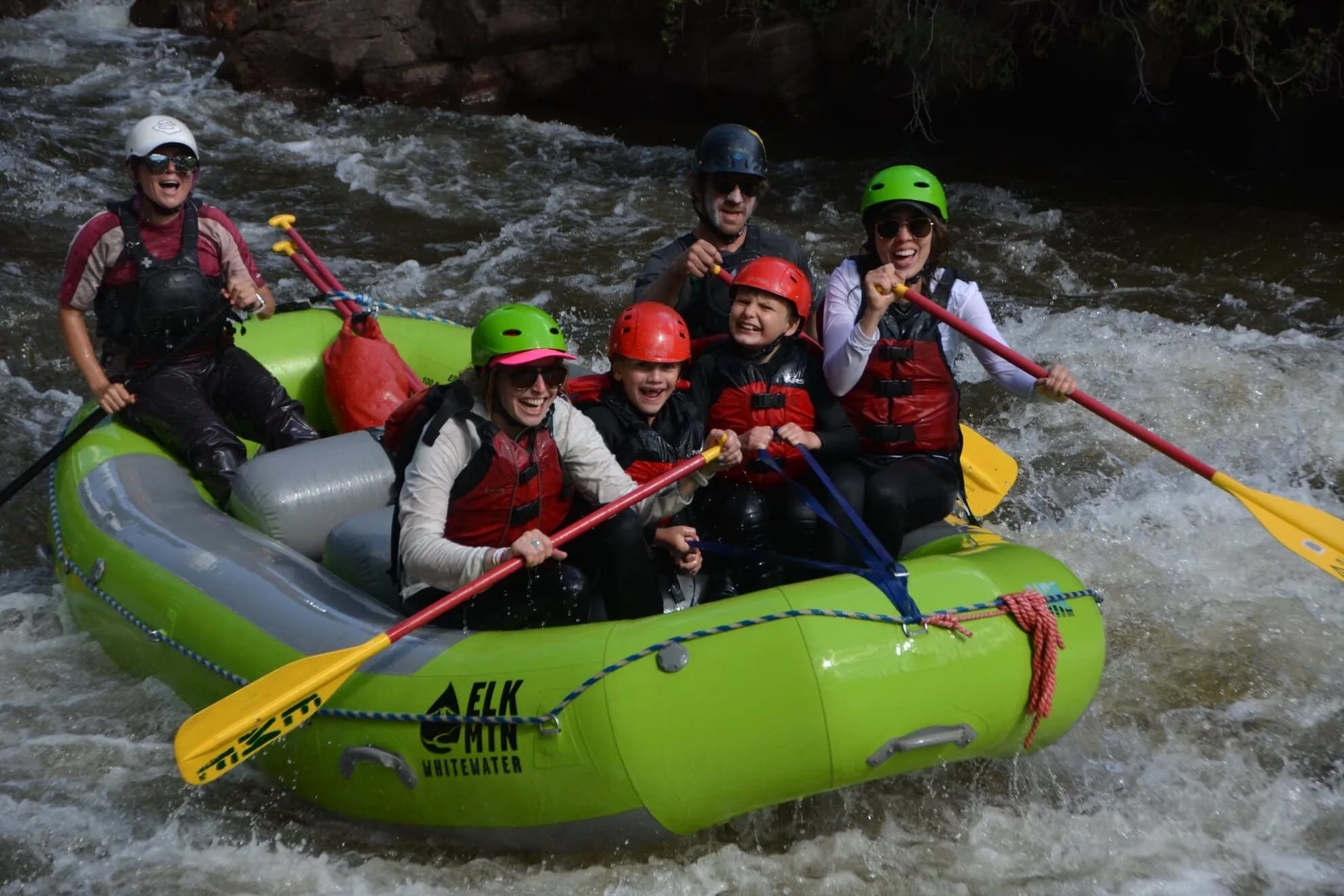 A group of people in a raft navigate white water rapids.