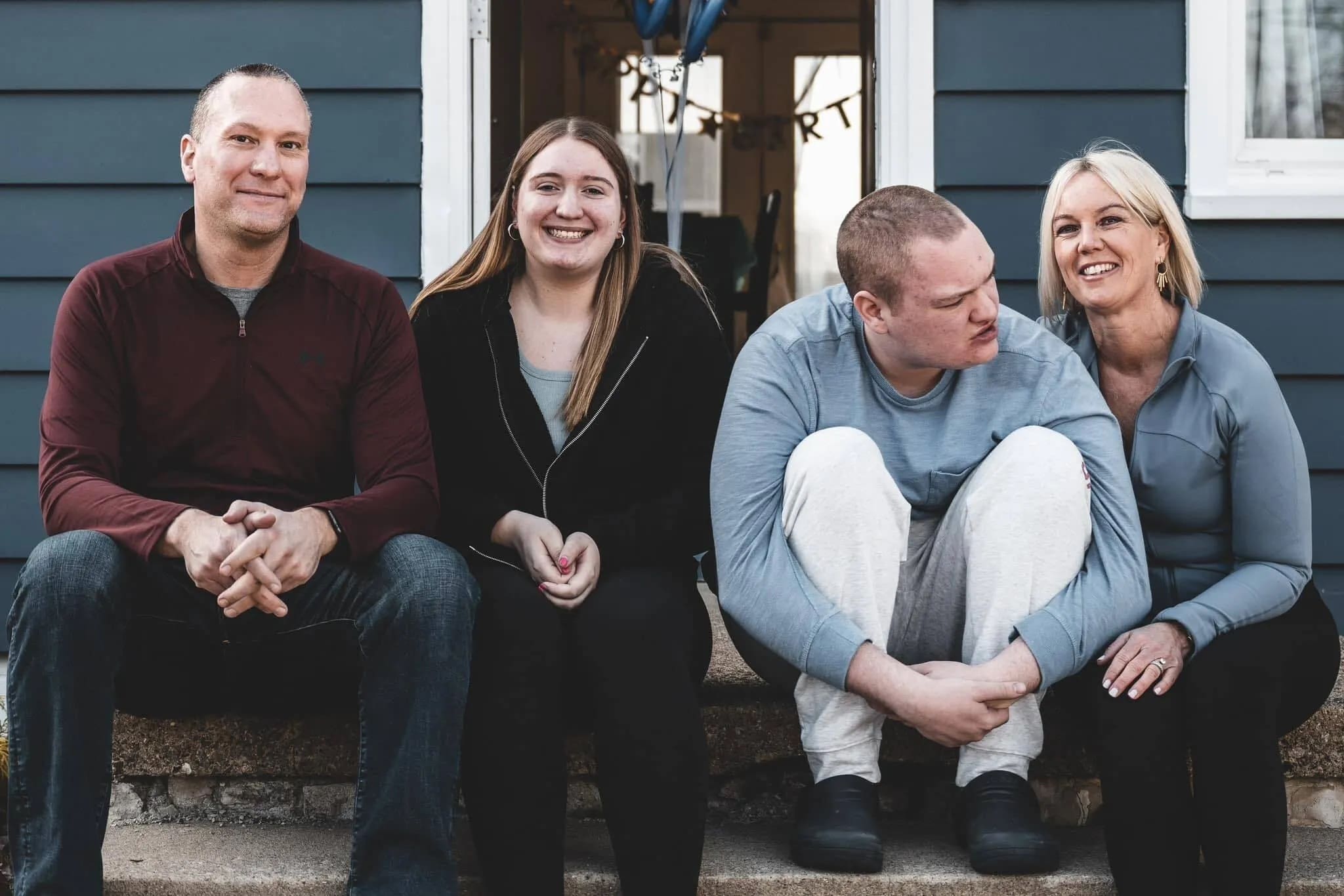 Amy Shope and family sitting on steps outside their home.