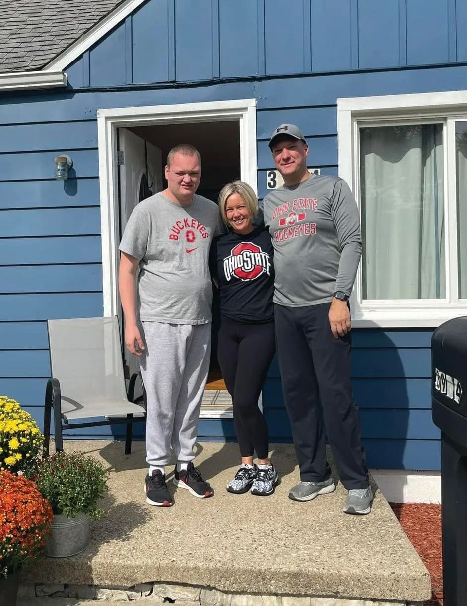 Amy Shope with two men outside a blue house.