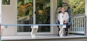 Amanda sits in a hanging chair on the porch of her tiny house.