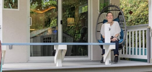 Amanda sits in a hanging chair on the porch of her tiny house.