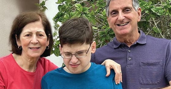 A woman, a young man, and an older man smile for a photo outdoors.