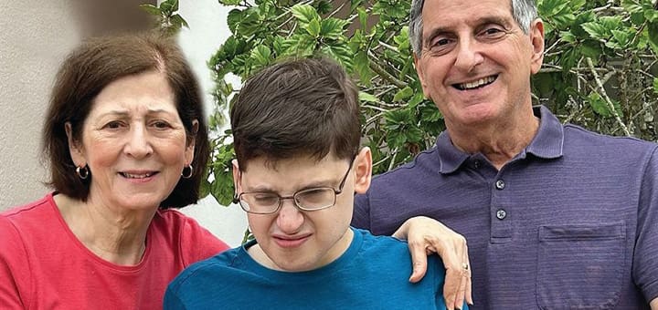 A woman, a young person, and a man smile at the camera.
