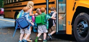 Children with backpacks boarding a yellow school bus
