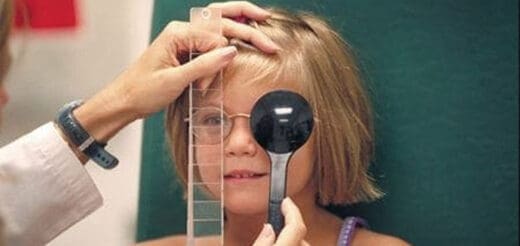 Child receives an eye exam with a vision chart and occluder.