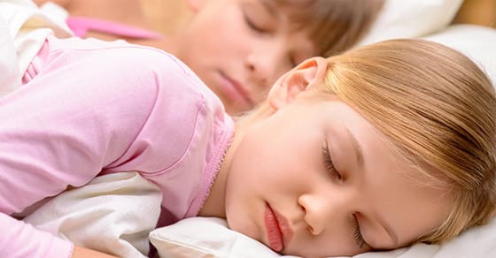 Two children sleeping peacefully in bed.
