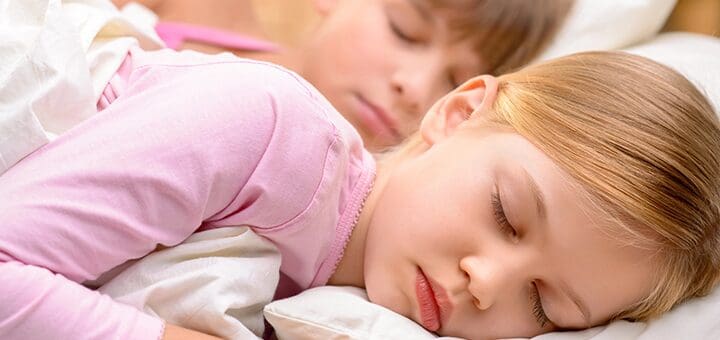 Two children sleeping soundly in bed.