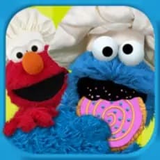 Elmo and Cookie Monster in chef hats with a cookie.