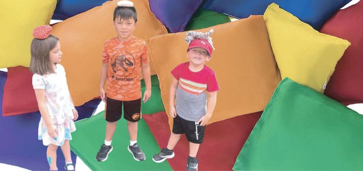 Children balance bean bags on their heads surrounded by bean bag chairs of various colors.