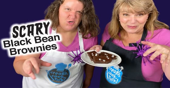 Two women hold a plate with a brownie and toy spiders, with "SCARY Black Bean Brownies" text.
