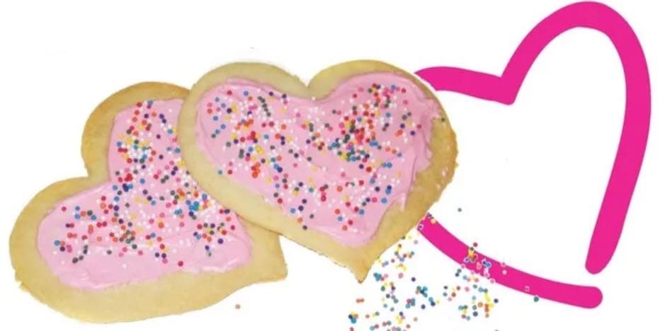 Two heart-shaped cookies with pink frosting and sprinkles next to a large pink heart outline.