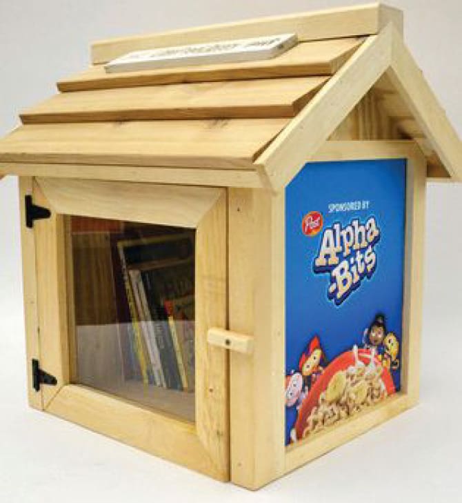Wooden community library with a "Sponsored by Alpha-Bits" sign