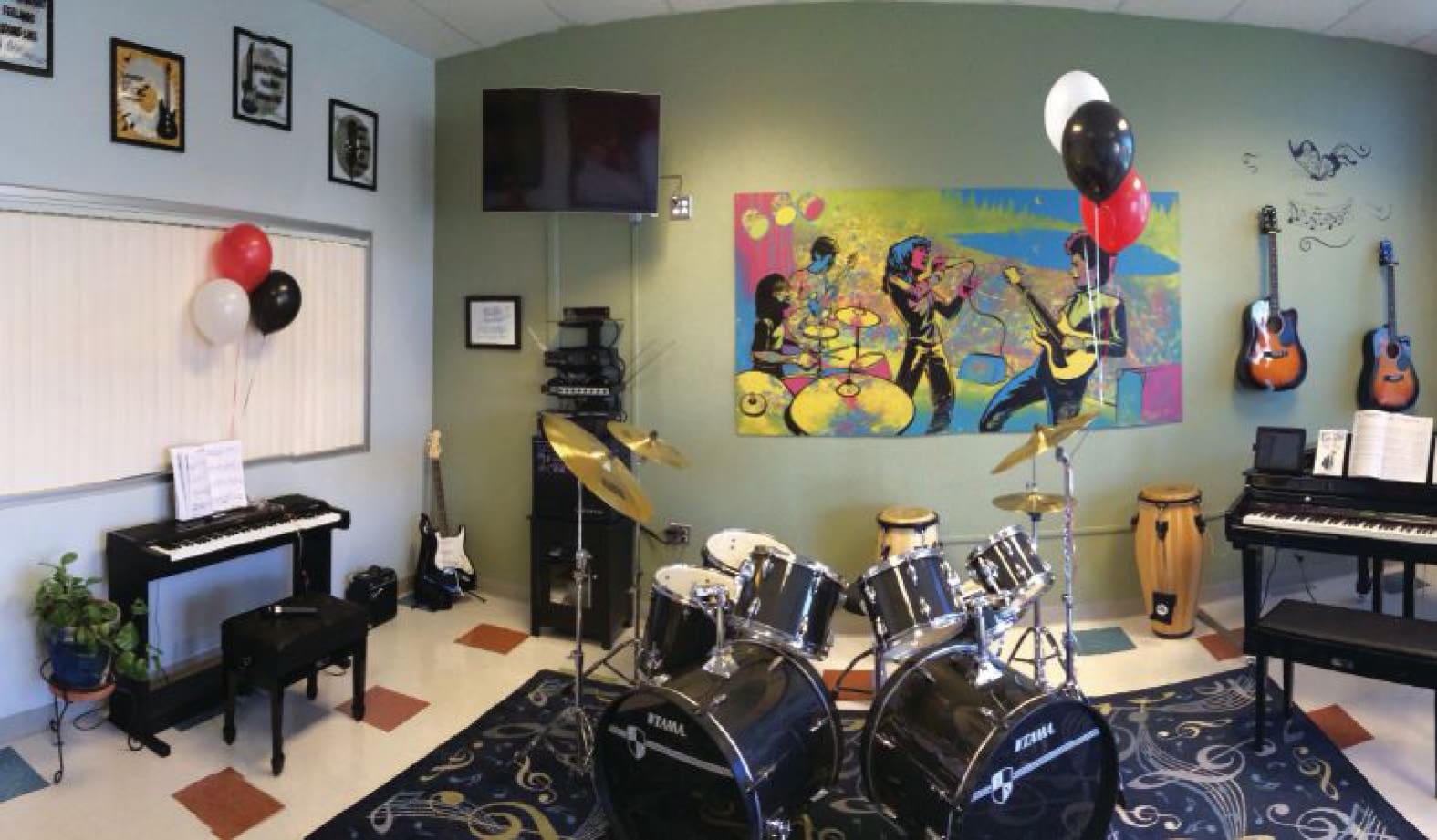 A music room with instruments including drum sets, keyboards, and guitars.