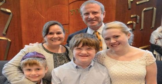 Phil Pedlikin with family members in front of a wooden background.