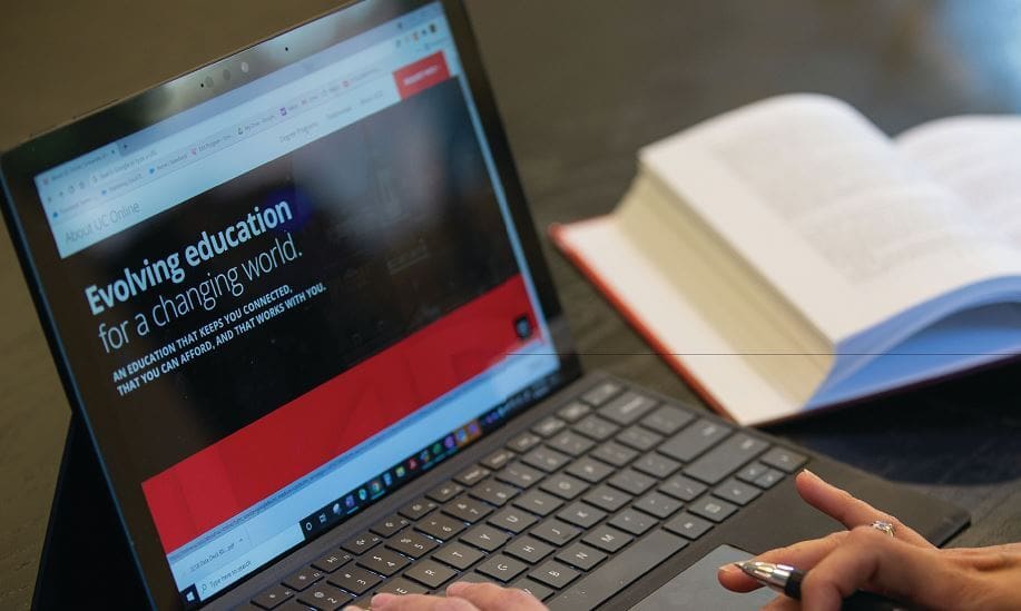 Laptop with text "Evolving education for a changing world" next to an open book.