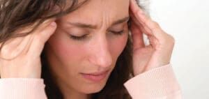 Woman holding her temples with a pained expression.